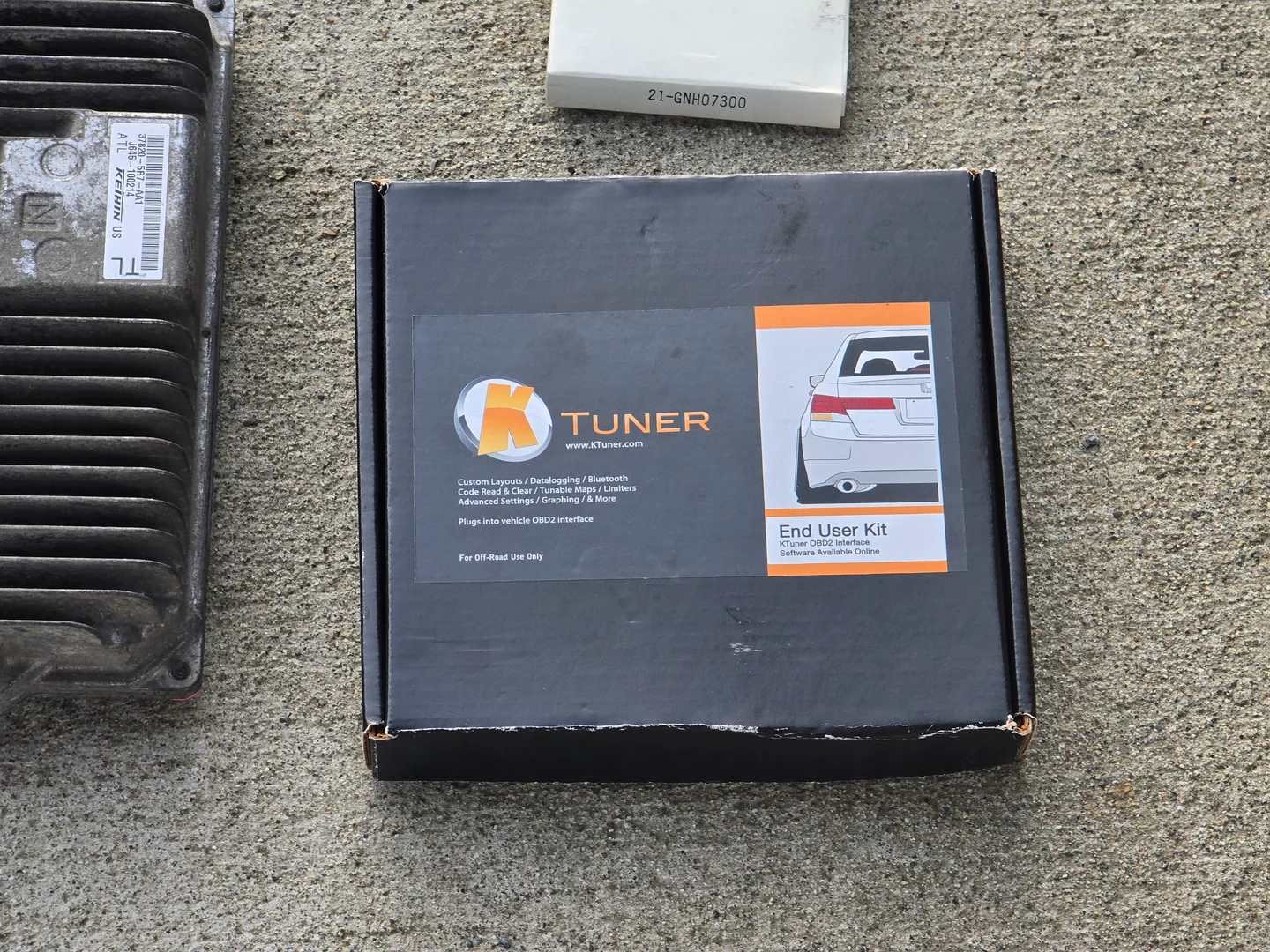 Un KTuner End User Kit junto a una ECU británica de Honda Fit usada mientras se investigaba soporte para un Fit japonés.