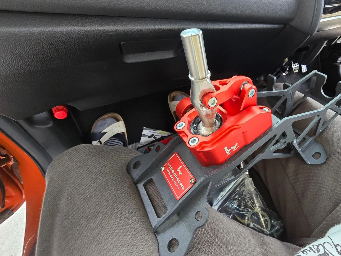 Short shifter rojo de Hybrid Racing sobre los asientos delanteros de un Honda Fit durante la instalación.