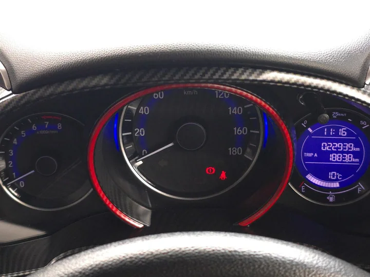 Cubierta de instrumentos J's Racing de fibra de carbono alrededor de los relojes iluminados del Honda Fit.