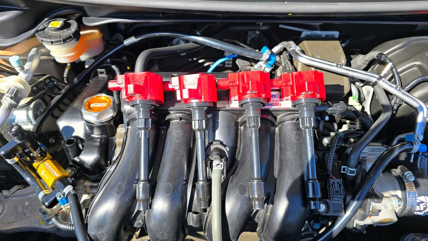 Motor L15B del Honda Fit con coils MSD rojos, sistema T-REV de J's Racing, tapa Mugen e intake Takeda.