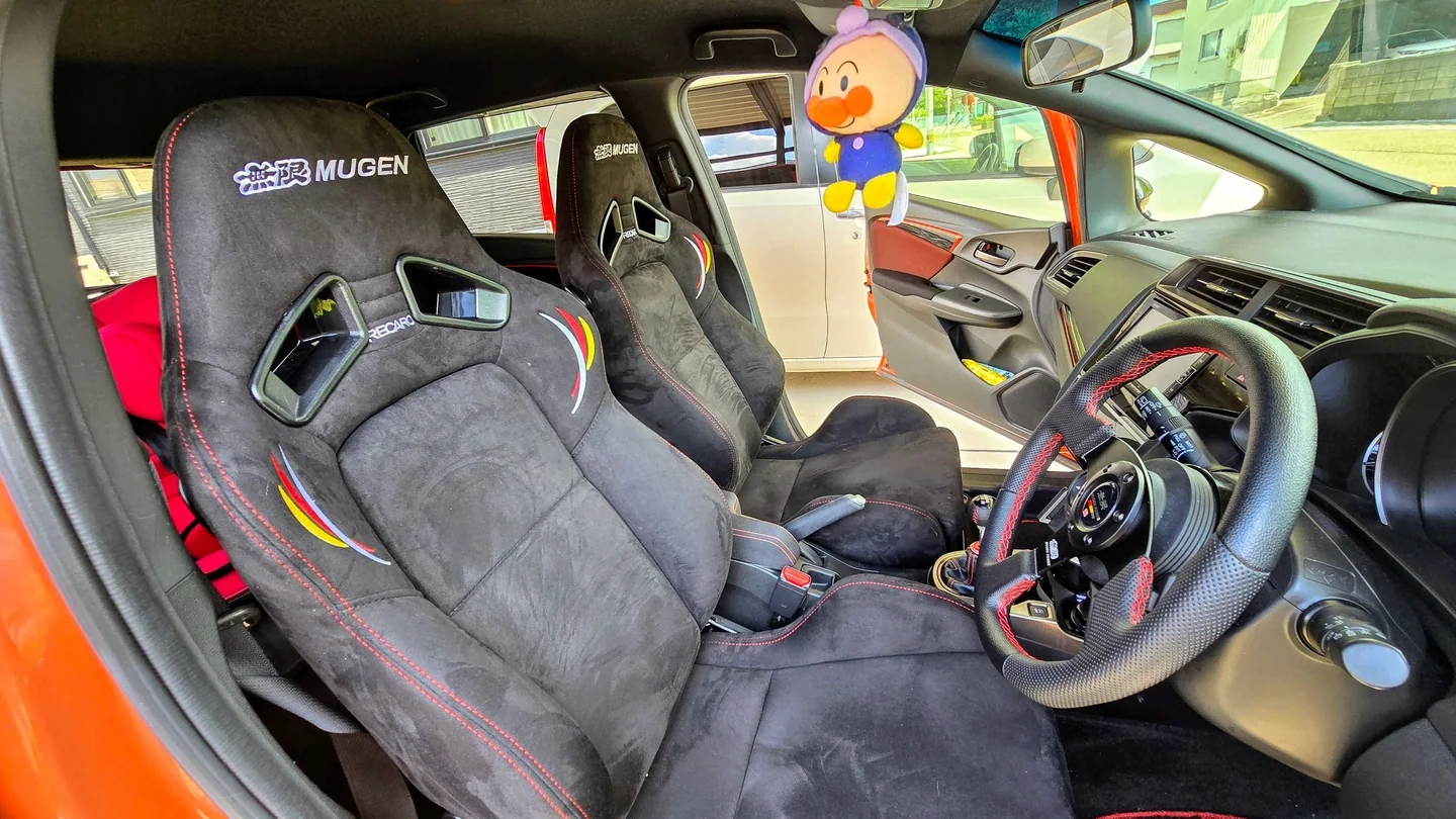 Interior del Honda Fit con asientos Mugen Recaro, guía Mugen, controles conservados y palanca manual.