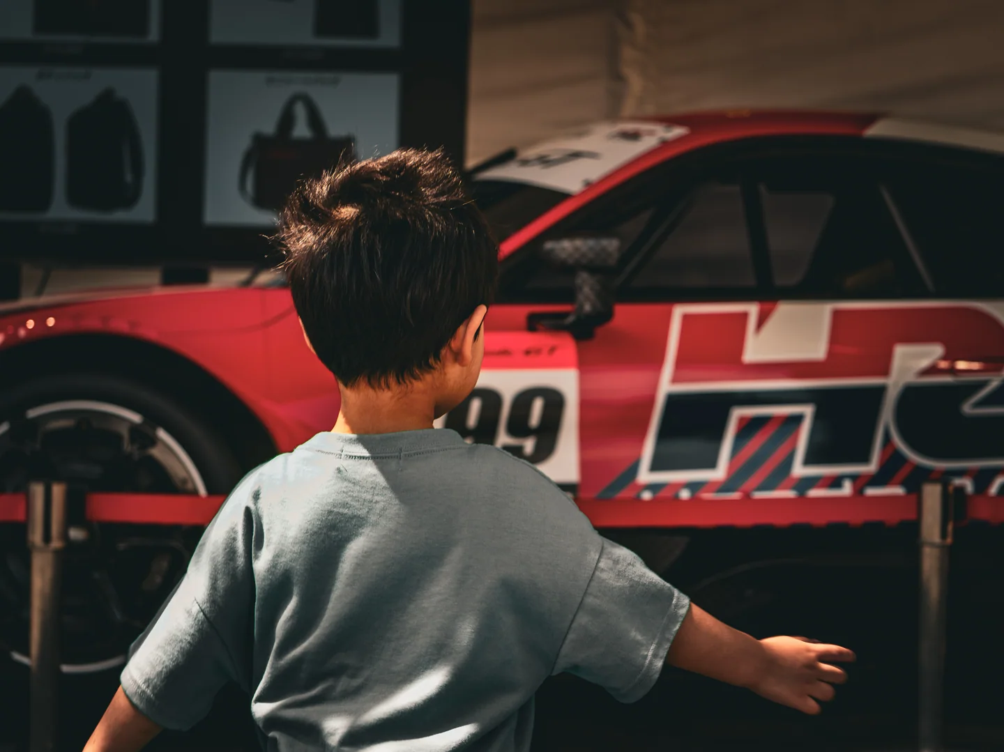 Harry's youngest son reaches toward the red, white, and black No. 99 Honda HRC Prelude-GT development car.