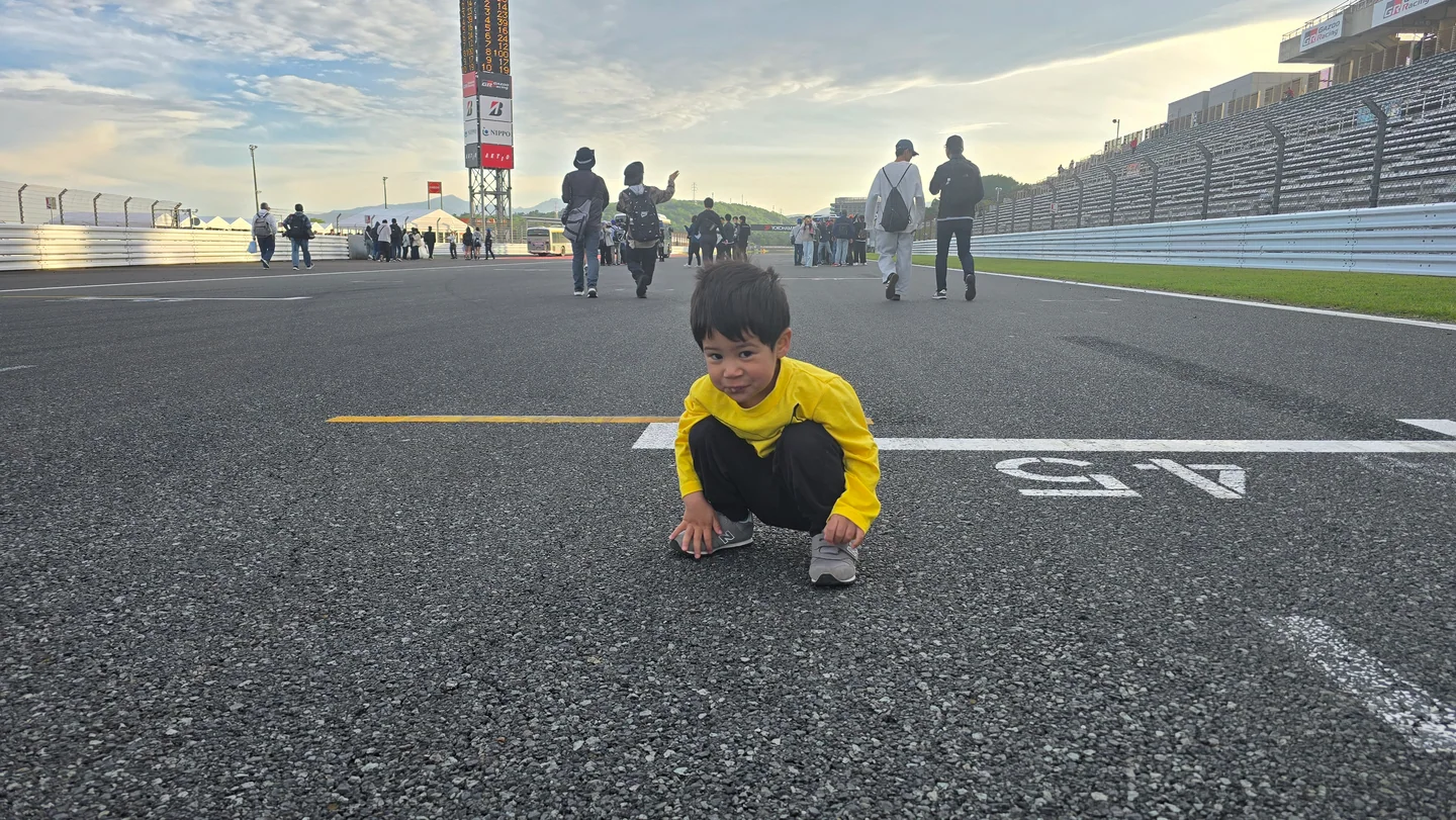 Harry's youngest son crouches over a painted grid position on the Fuji Speedway start-finish straight after the race.