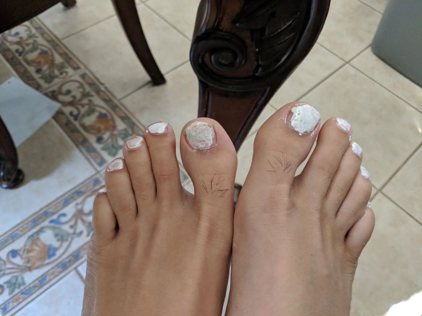 Toenails covered in a child's enthusiastic white nail polish.